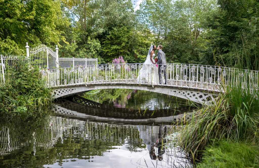 Bride and groom on the white bridge at Morden Hall reflected in the River Wandle
