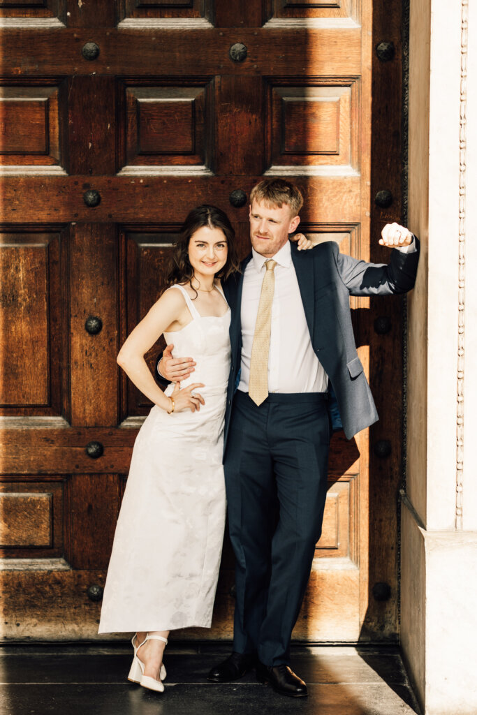 Bride and groom leaning on a door St Paul's cathedral.