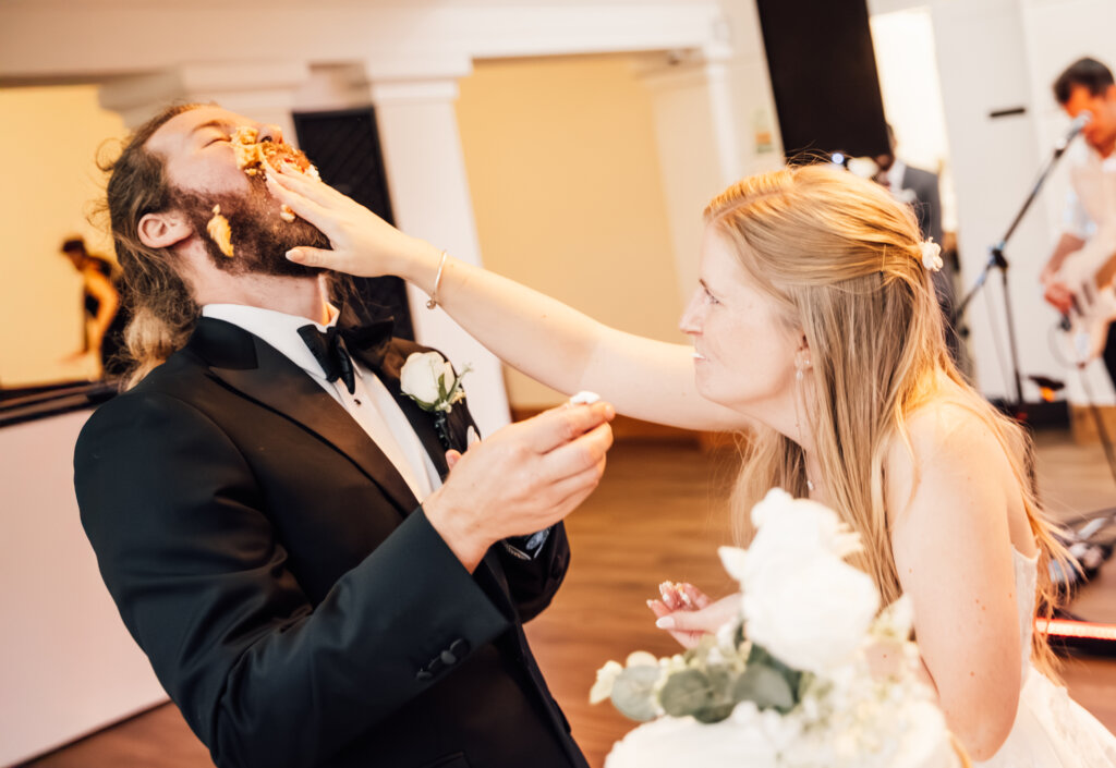Cake cutting, bride pushes some of the wedding cake in the groom's face.