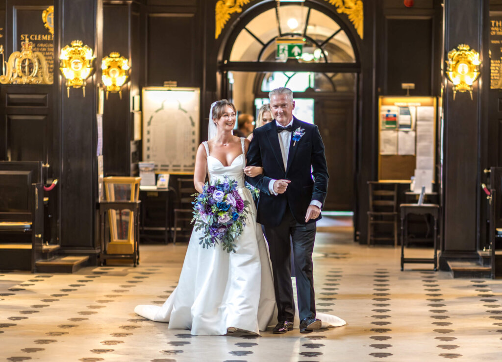 Bride looks at her dad as they walk down the aisle.